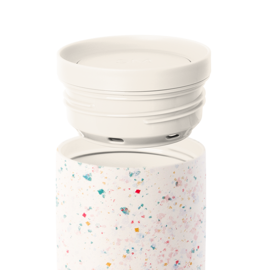 Cream-colored two-piece cookware set with removable lid on white background, featuring a light cream base vessel and off-white top component.