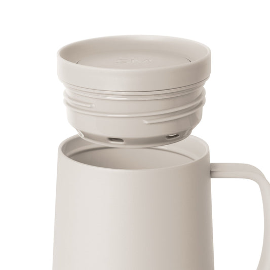 Cream-colored cylindrical tumbler with matching lid on plain background