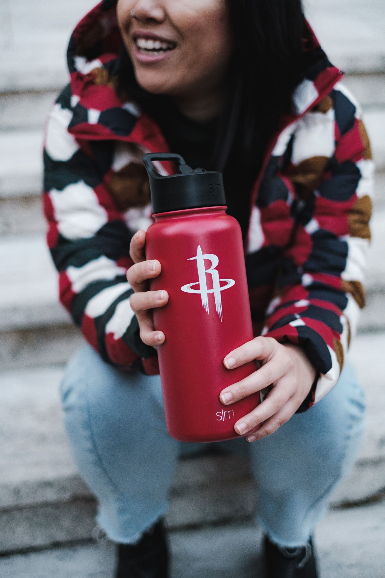 Red water bottle with crimson finish against cool-toned background