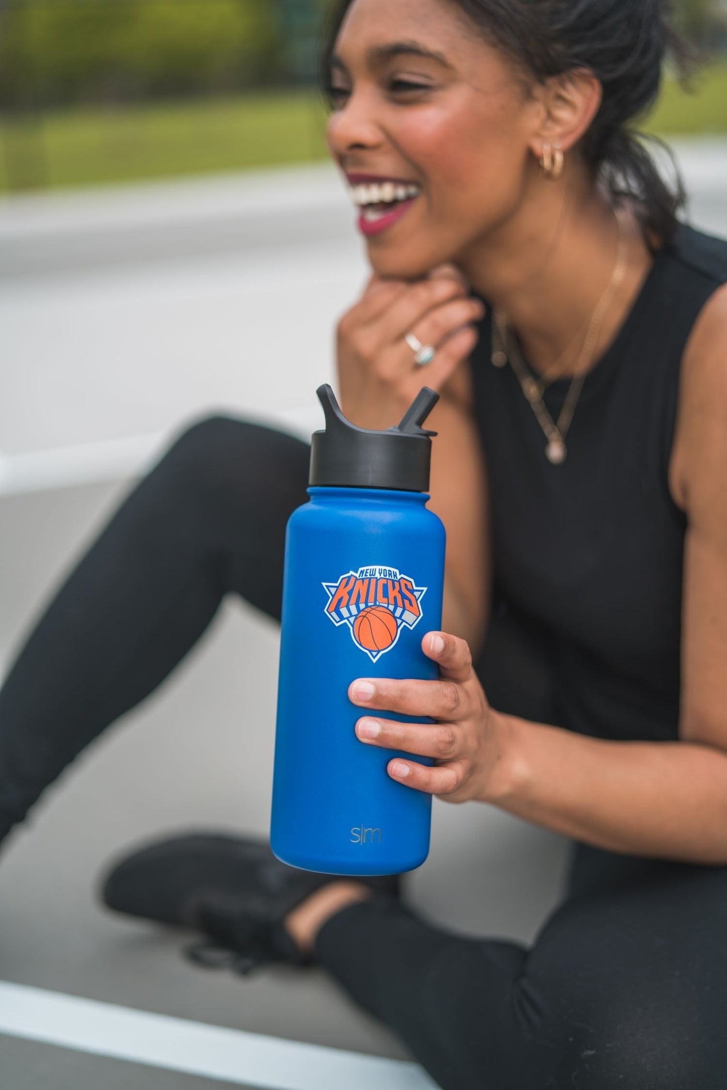 Woman in outdoor setting holding a bright royal blue water bottle