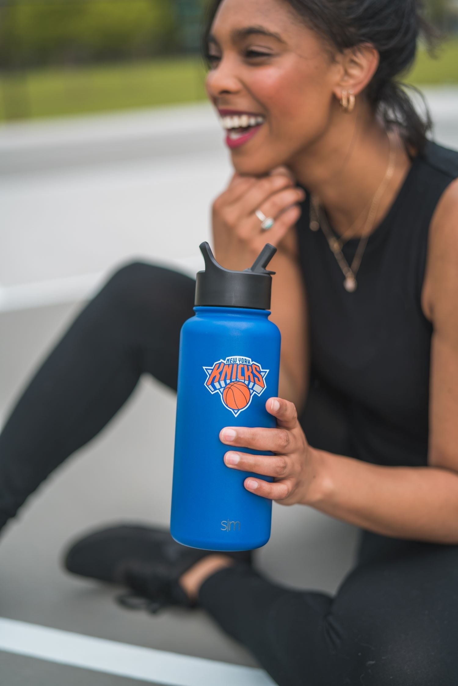 Royal blue water bottle with black lid and accents held by person in athletic wear