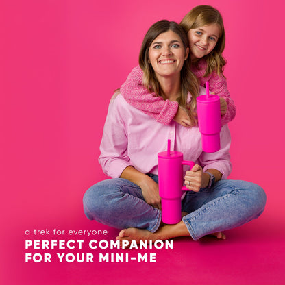 Child and adult wearing matching soft pink and mauve outfits standing against vibrant hot pink background, showcasing coordinating family look.