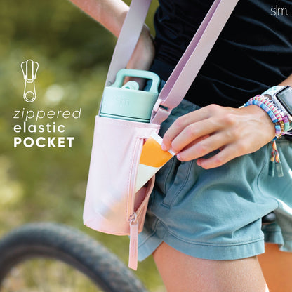 Pastel-colored kids' sling bag in light pink, mint green, and dusty blue with blurred green outdoor background