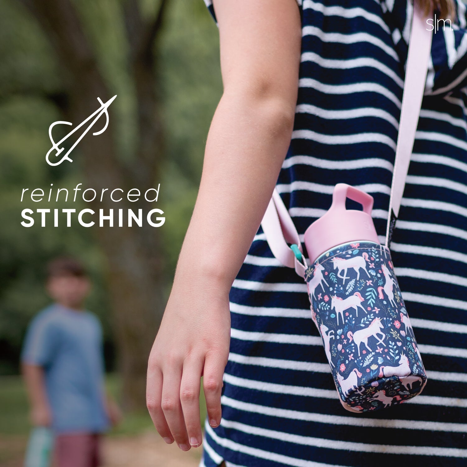 Child wearing navy blue and white striped adventure sling against a blurred natural gradient background