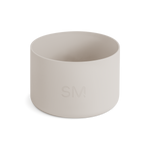 Off-white matte cylindrical boot product on pale beige background. Neutral, warm cream color palette with soft lighting.
