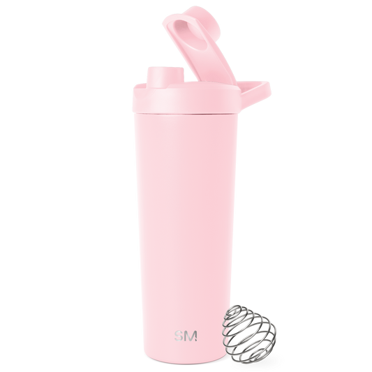 Pale pink cylindrical insulated tumbler with secure lid and carry handle against white background, featuring matte finish and minimalist design.