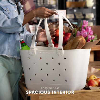 White Simple Modern tote bag displaying spacious interior, styled with soft sage green pants and light blue denim jacket