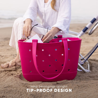 Woman in lavender linen shirt holding a hot pink tote bag on a sandy beach background, demonstrating the bag's tip-proof design and durability.