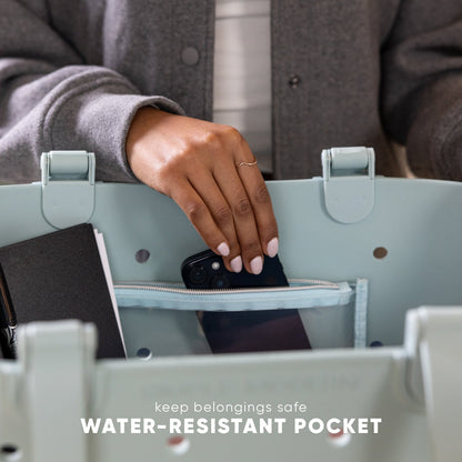 Sage green water-resistant getaway tote bag with open interior pocket displaying brown lining, showcasing durable fabric construction and functional design for travel.