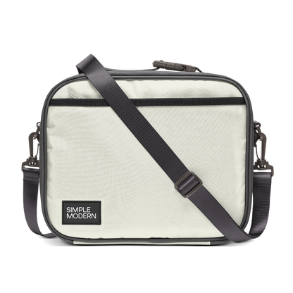 Light cream canvas tote bag with charcoal gray trim, black webbing straps, and dark hardware. Front view of structured handbag with contrasting accent details.