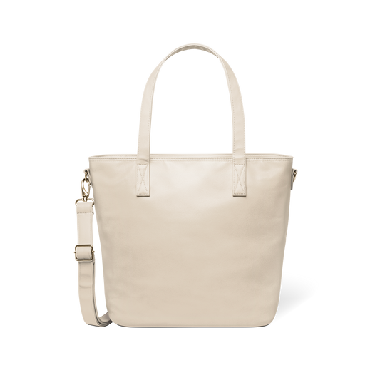 Oatmeal-colored tote bag with gold-toned metal hardware and handles against a white background