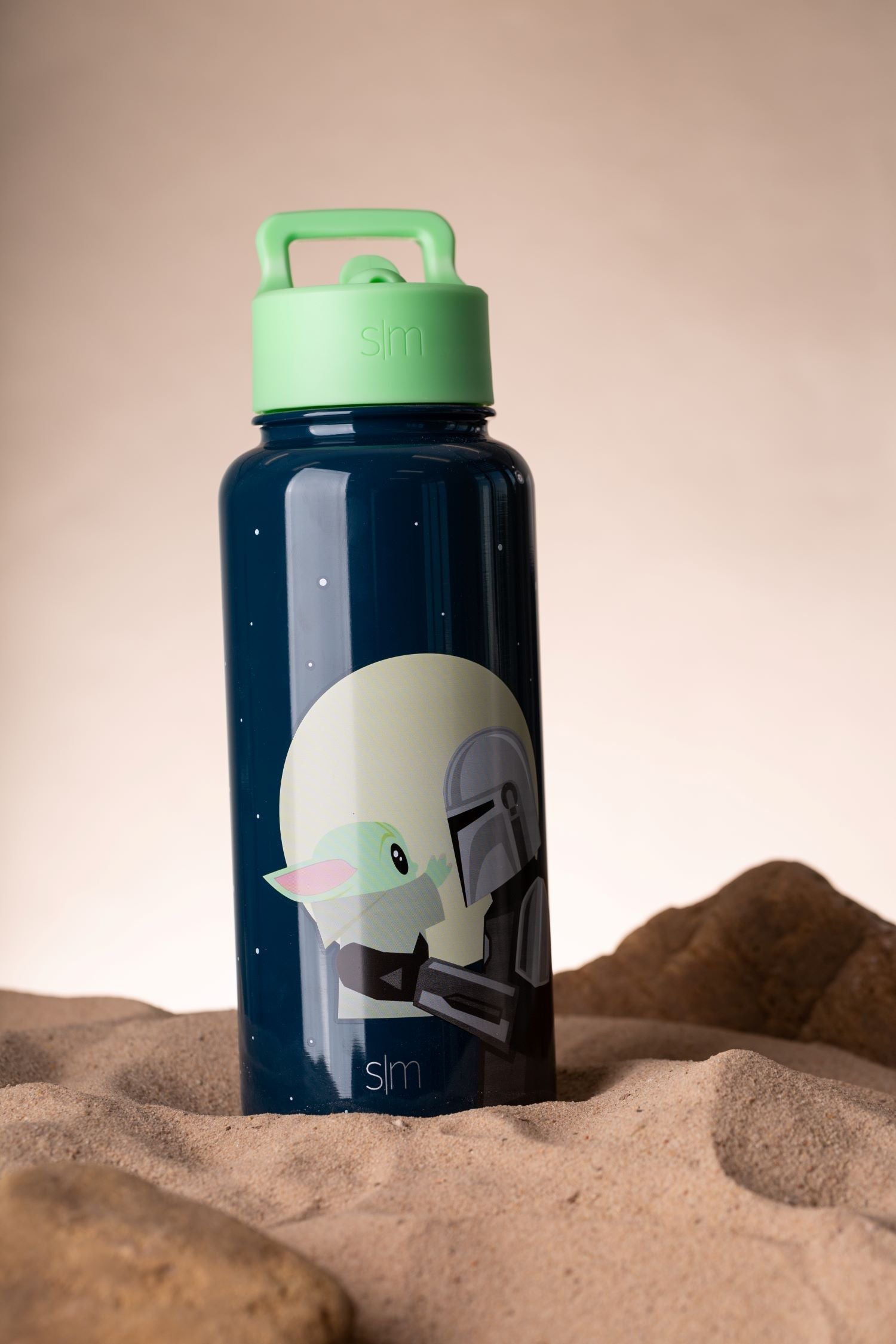 Navy blue water bottle with mint green cap and handle on sandy background