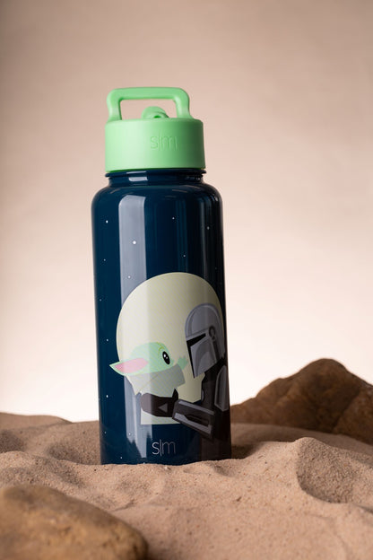 Navy blue water bottle with mint green cap and handle on sandy background