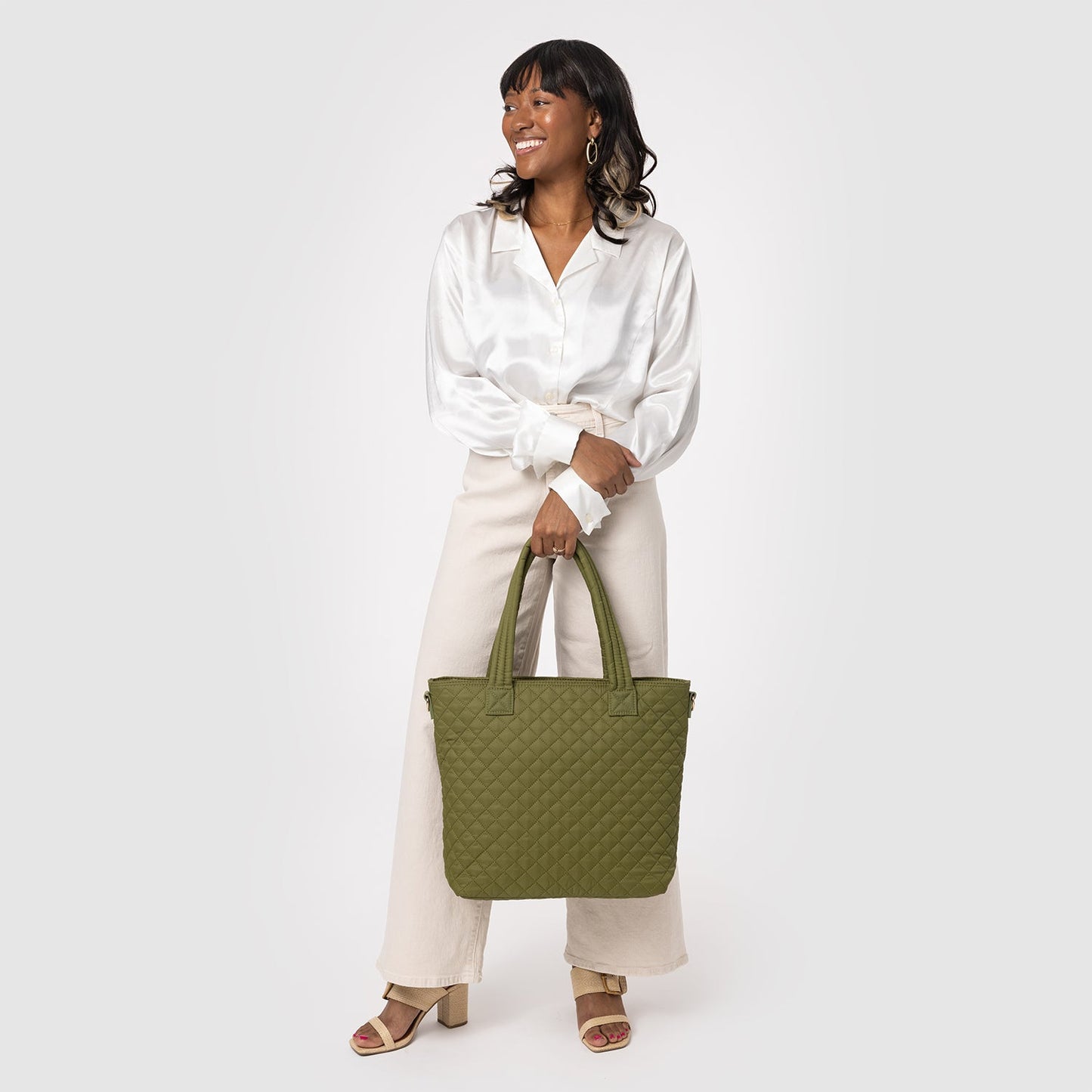 Woman wearing a crisp white long-sleeve button-front blouse and cream-colored wide-leg pants against a neutral background.