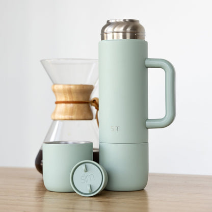 Sage green drinkware collection displayed with natural wood and stainless steel accents on a soft, neutral background