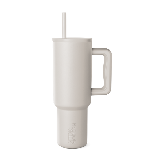 Beige signature tumbler with handle and straw on neutral background