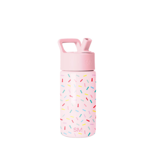 Simple Modern children's water bottle with soft pink body, colorful confetti pattern, screw-on cap with SM logo, pop-up straw spout, and carry handle on white background.