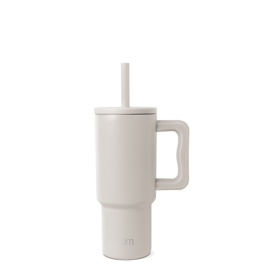 Cream-colored tumbler with handle and reusable straw, modern design with warm beige undertones