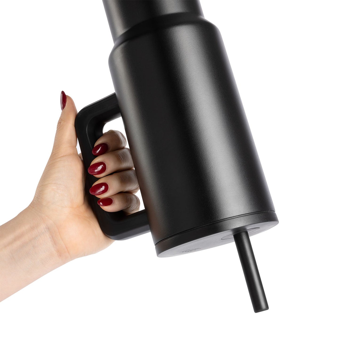Woman holding black matte stainless steel water bottle by handle against white background, wearing deep burgundy nail polish