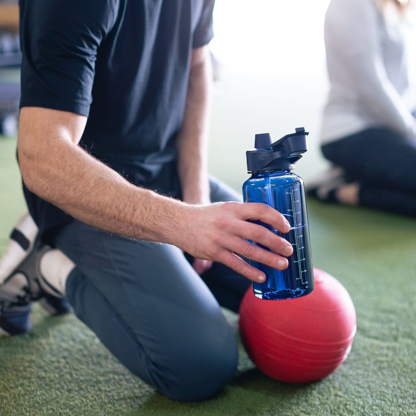Blue Simple Modern water bottle with black flip-top lid next to a red exercise ball