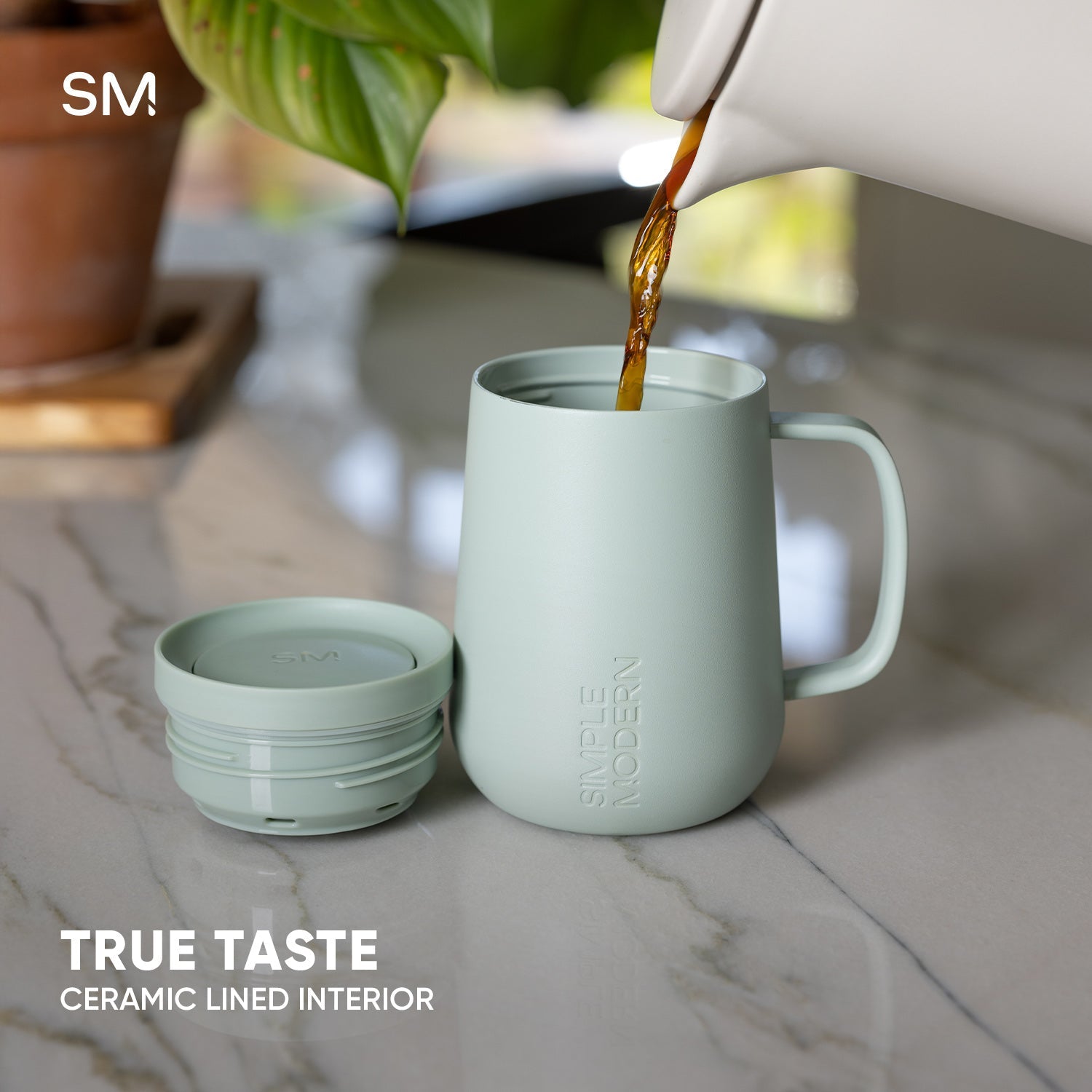 Ceramic-lined Voyager360 mug with mint green exterior as hot liquid in amber and golden brown tones is being poured into it