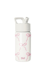 White Simple Modern water bottle with pink bow pattern, wide-mouth design, white screw-on cap with handle and straw opening, SM logo on lid and lower body, studio product shot on white background.