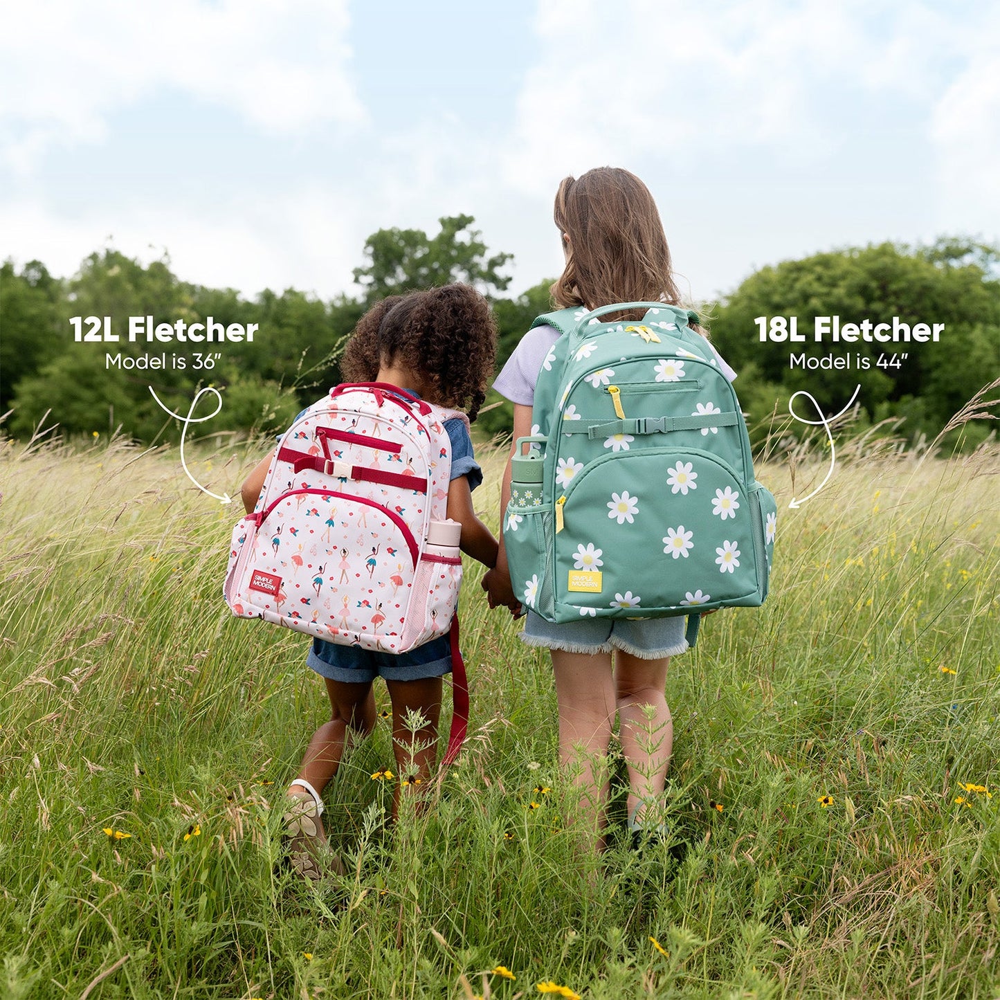 Two children viewed from behind wearing different sized Fletcher backpacks against a concrete wall. Left child, 43 inches tall, wears 12L rainbow striped backpack. Right child, 48 inches tall, wears 18L pink backpack with