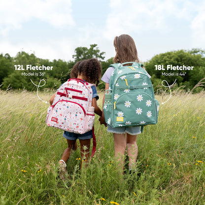 Two children viewed from behind wearing different sized Fletcher backpacks against a concrete wall. Left child, 43 inches tall, wears 12L rainbow striped backpack. Right child, 48 inches tall, wears 18L pink backpack with