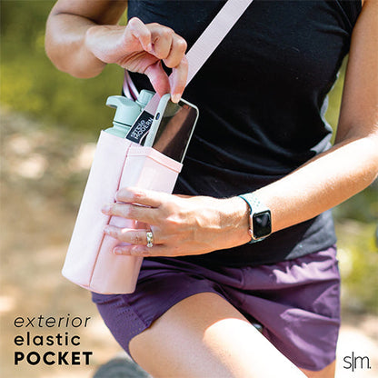 Person wearing black sleeveless athletic top and purple shorts holding a pale pink water bottle
