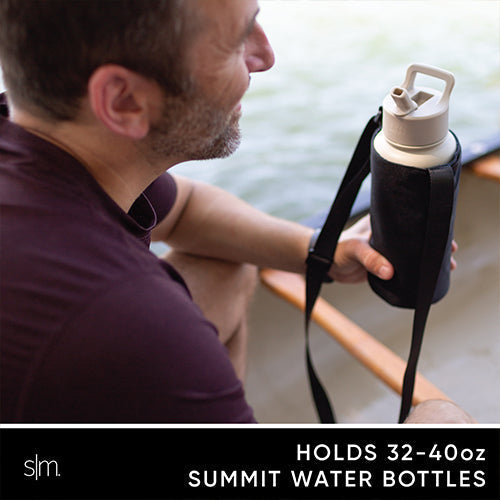 Man in burgundy shirt holding a Simple Modern water bottle carrier with cream cap and black neoprene material, looking toward water