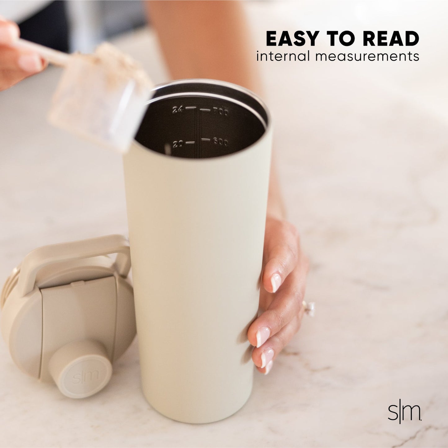 Cream-colored insulated tumbler with black lid featuring white measurement markings on the interior, displayed against a neutral background.