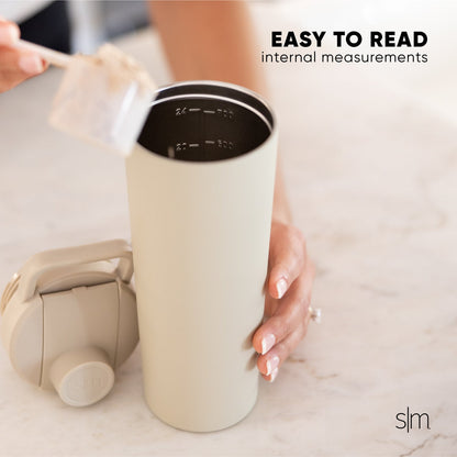 Cream-colored insulated tumbler with black lid featuring white measurement markings on the interior, displayed against a neutral background.